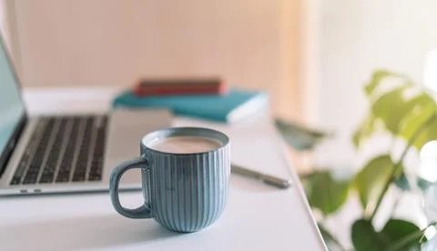 Laptop with coffee cup on desktop with notepad Stock-Fotos