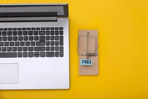 Laptop computer and mouse trap with free sign on yellow background Stock Photos