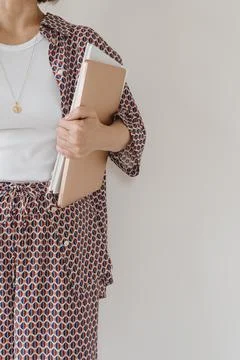 Laptop computer and paper documents in female hand. Young pretty woman in paj Stock Photos