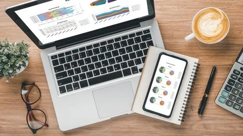 Laptop computer and smart phone with charts and reports on screen display o.. 스톡 사진