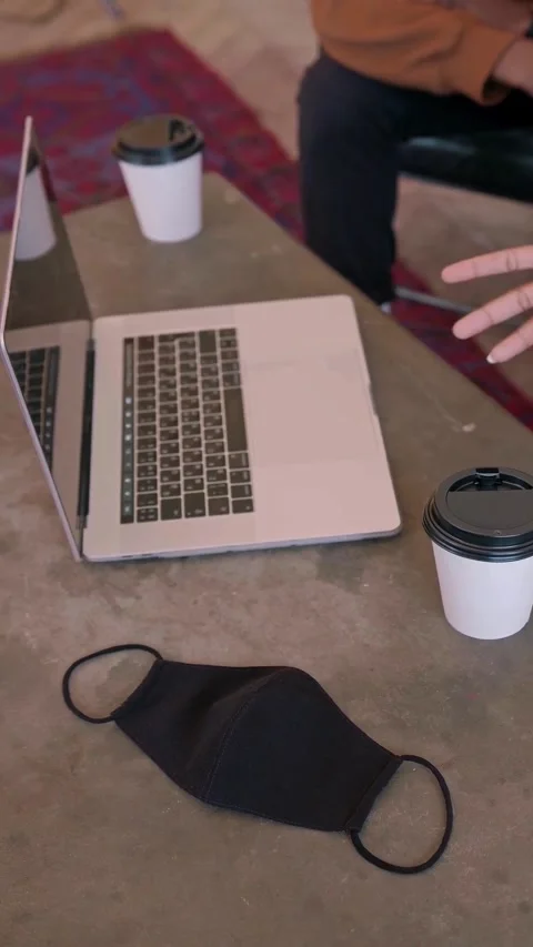 Laptop computer with black face mask and coffee cups on table Stock Footage 348269486