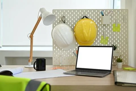 Laptop computer with blank screen, blueprints, hardhat and jacket on wooden Stock Photos