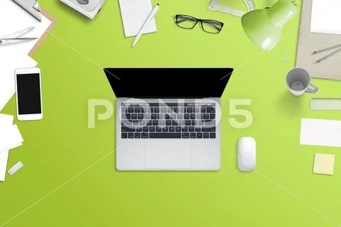 Laptop computer with blank screen on green desk surrounded with phone, papers Stock Photos