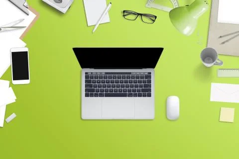 Laptop computer with blank screen on green desk surrounded with phone, papers 写真素材