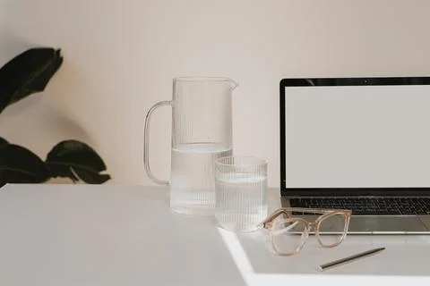 Laptop computer with blank white screen, decanter and glass of clean pure wat Stock Photos