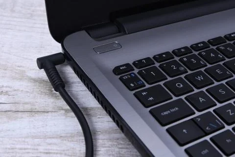 Laptop, computer is charging from a 220-volt outlet on a desk near the wall. Stockfoto's