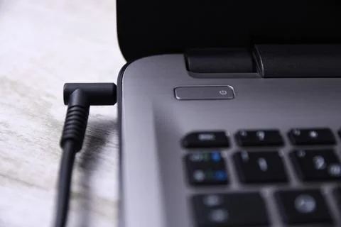 Laptop, computer is charging from a 220-volt outlet on a desk near the wall.  스톡 사진