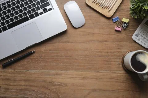 Laptop computer, coffee cup, potted plant and calculator on wooden table. Fla Stock Photos