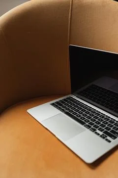 Laptop computer on comfortable orange lounge chair Stock Photos