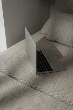 Laptop computer on comfortable sofa with sunlight shadows Stock Photos