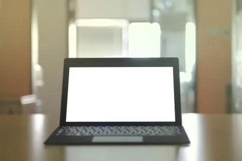 Laptop computer displaying white background. PC on a table in a office room. Stock Photos