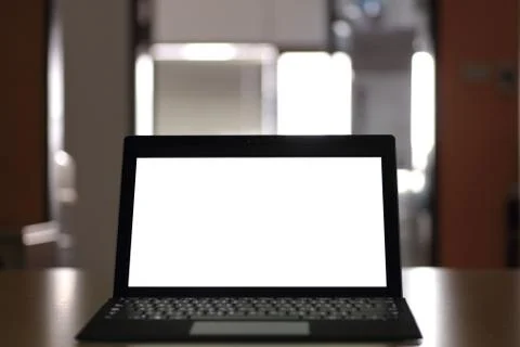 Laptop computer displaying white background. PC on a table in a office room. Stock Photos