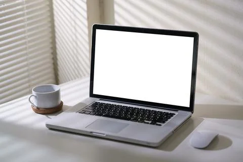 Laptop computer with empty display and cup of coffee on white table in brig.. Stock Photos