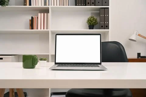 A laptop computer with empty display and office supplies on a desk in front of a Stock Photos