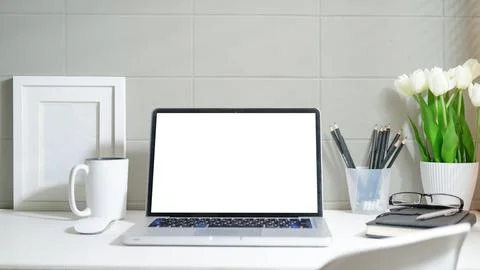 Laptop computer with empty screen, coffee cup, picture frame and stationery.. Stock Photos