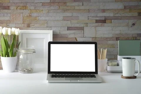 Laptop computer with empty screen, flower pot, coffee cup and picture frame o Stock Photos