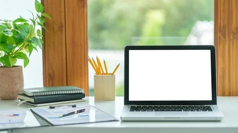 Laptop computer with empty screen, stationery and potted plant on white tab.. Stock Photos
