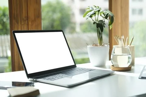 Laptop computer with empty screen, stationery and potted plant on white tab.. Stock Photos
