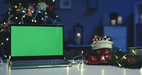 Laptop computer with a green screen at the Christmas tree on the table at the Stock Footage 99808333
