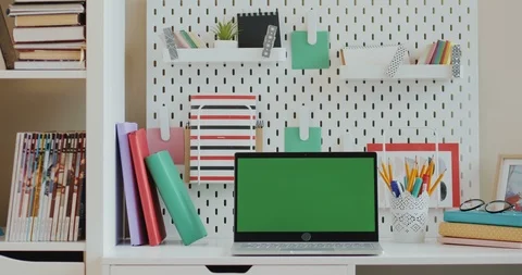 Laptop computer with green screen on the desk with books and other stuff in the Video stock 104207379