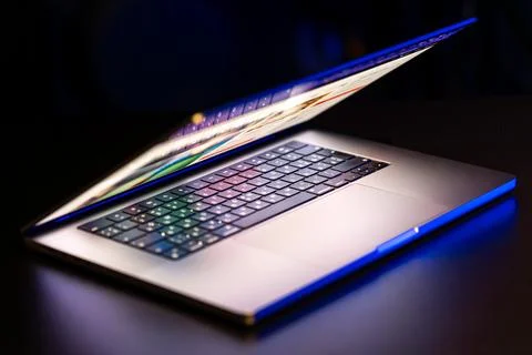 A laptop computer with a half-open screen on a dark background. Stock Photos