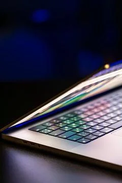 A laptop computer with a half-open screen on a dark background. Copy space. Stock Photos
