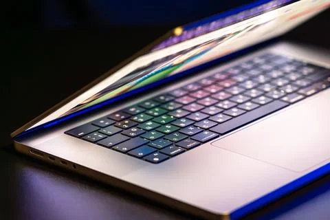 A laptop computer with a half-open screen on a dark background. Stock Photos