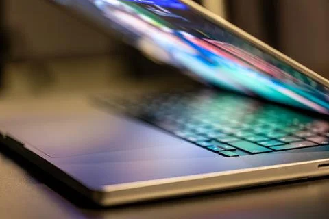 A laptop computer with a half-open screen on a dark background. Stock Photos