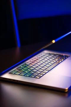 A laptop computer with a half-open screen on a dark background. Copy space. Stock Photos
