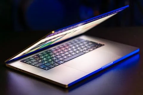 A laptop computer with a half-open screen on a dark background. Stockfoto's