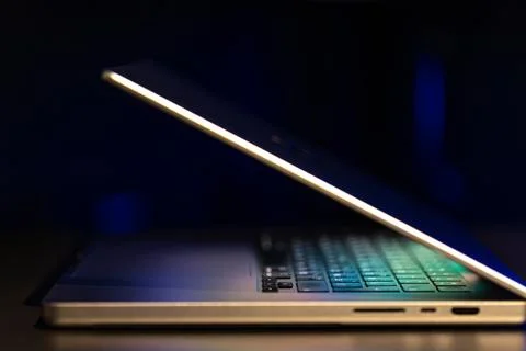 A laptop computer with a half-open screen on a dark background. Stock Photos