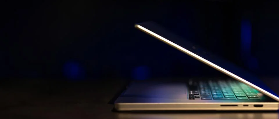 A laptop computer with a half-open screen on a dark background. Copy space. Stock Photos