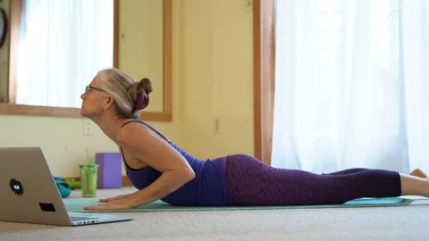 With a laptop computer to her side, a mature woman gets instruction and does a Stock Footage 128638563