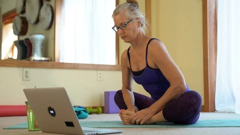 With a laptop computer to her side, a mature woman gets instruction and does Video stock 128638988