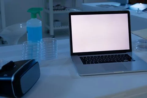 Laptop computer with illuminated screen at workstation in medical laboratory Stock Photos