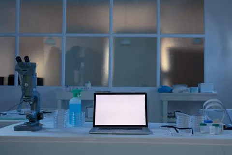 Laptop computer with illuminated screen at workstation in medical laboratory Stock Photos