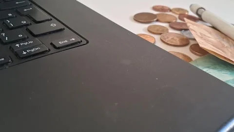 Laptop computer keyboard with scattered brazilian currency in motion video Stock Footage 339091157