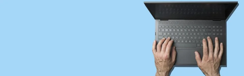 Laptop computer keyboard with user hands on blue minimal stylish background Stock Photos