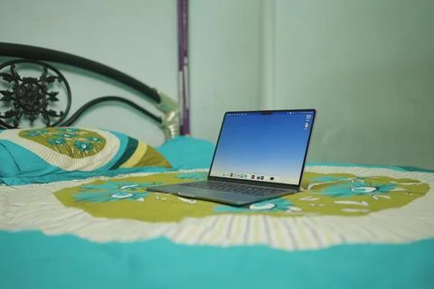 A laptop computer macbook sitting on top of a bedspread. Stock Photos