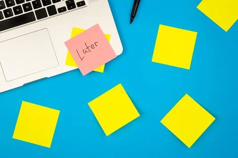 Laptop computer with many sticky notes on a blue background, flat lay. Stock Photos