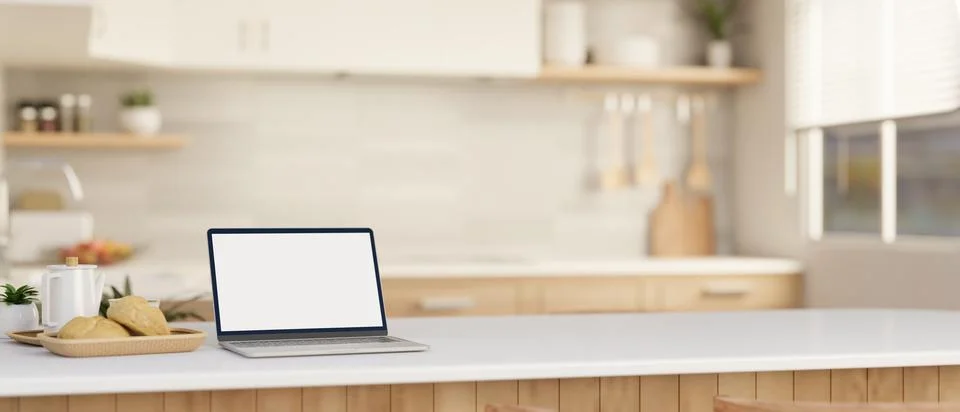 A laptop computer mockup on a white kitchen island or countertop in a moder.. イラスト素材