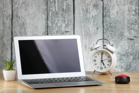 Laptop, computer mouse and keyboard on a table. Retro alarm clock. Stock Photos