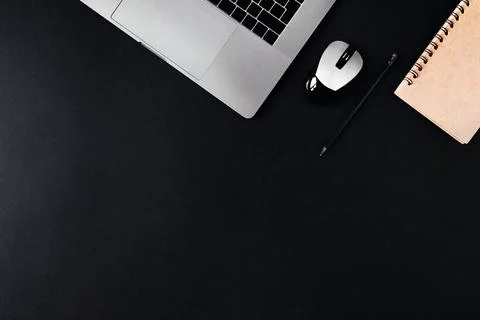 Laptop, computer mouse and notepad on a black background. Stock Photos