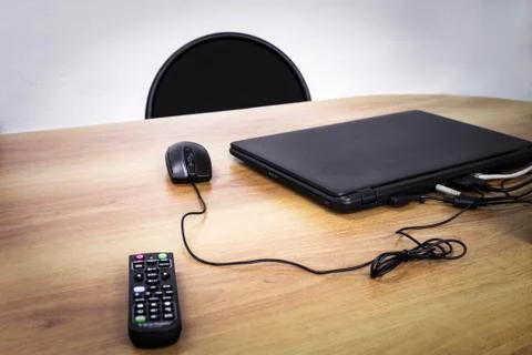 Laptop, computer mouse and remote control on desk Stock Photos