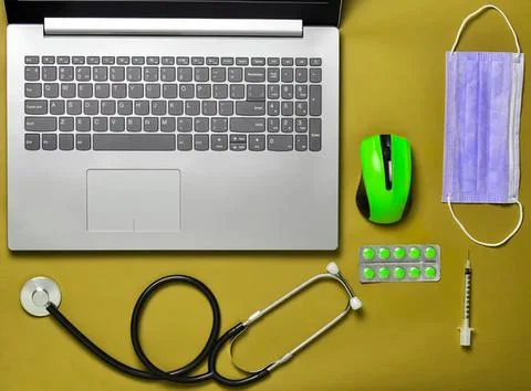 Laptop computer, mouse, stethoscope, and face mask on wooden desk Stock Photos