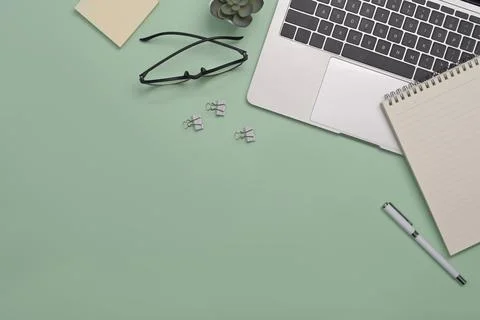 Laptop computer, notebook, sticky note, coffee cup and glasses on green 写真素材