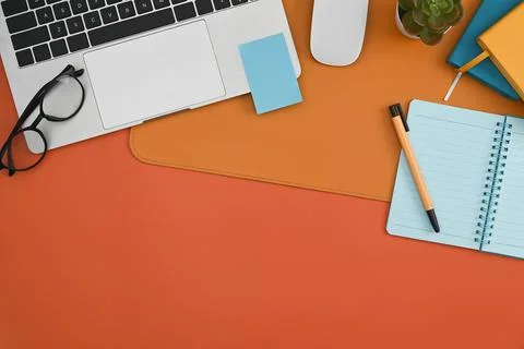 Laptop computer, notebook, sticky note and eyeglasses on orange background. 写真素材