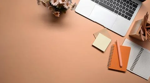Laptop computer, notebook, sticky notes and pencil holder on beige background. Stock Photos