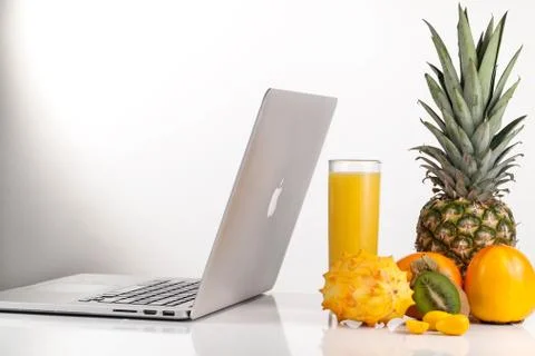 Laptop computer placed near composition of tropical fruits on a white table Foto stock