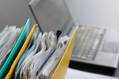 Laptop computer with ring binders filled with papers on office table Stock Photos